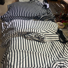 Pila de remeras rayados en proceso de confección sobre mesa de trabajo.