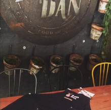 Delantal de denim negro con bolsillos y bordado de Forest Dan sobre una mesa en el local gastronómico.