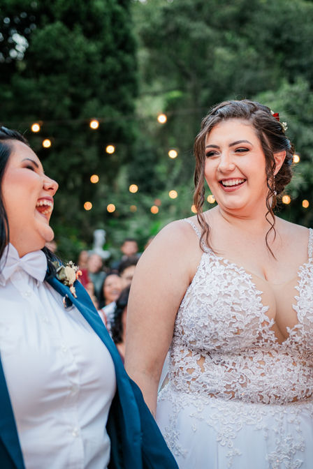 Duas noivas sorriem uma para outra durante a cerimônia de casamento