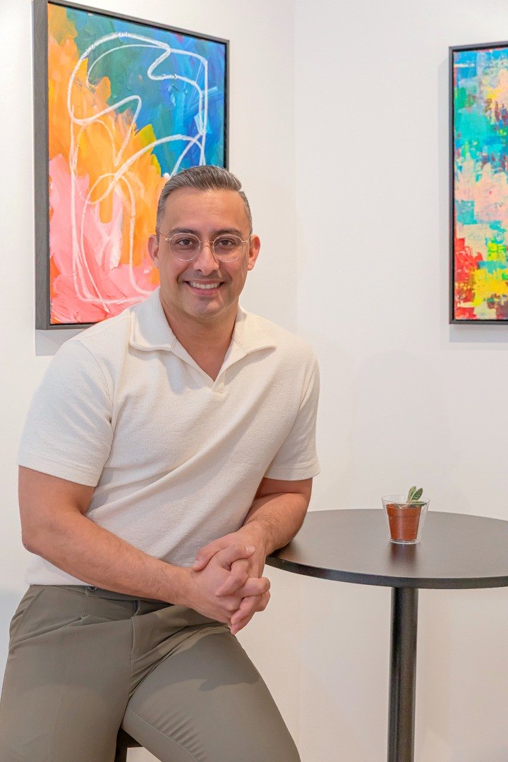 Edward leaning on a stool beside his paintings at Ecos y reflejos