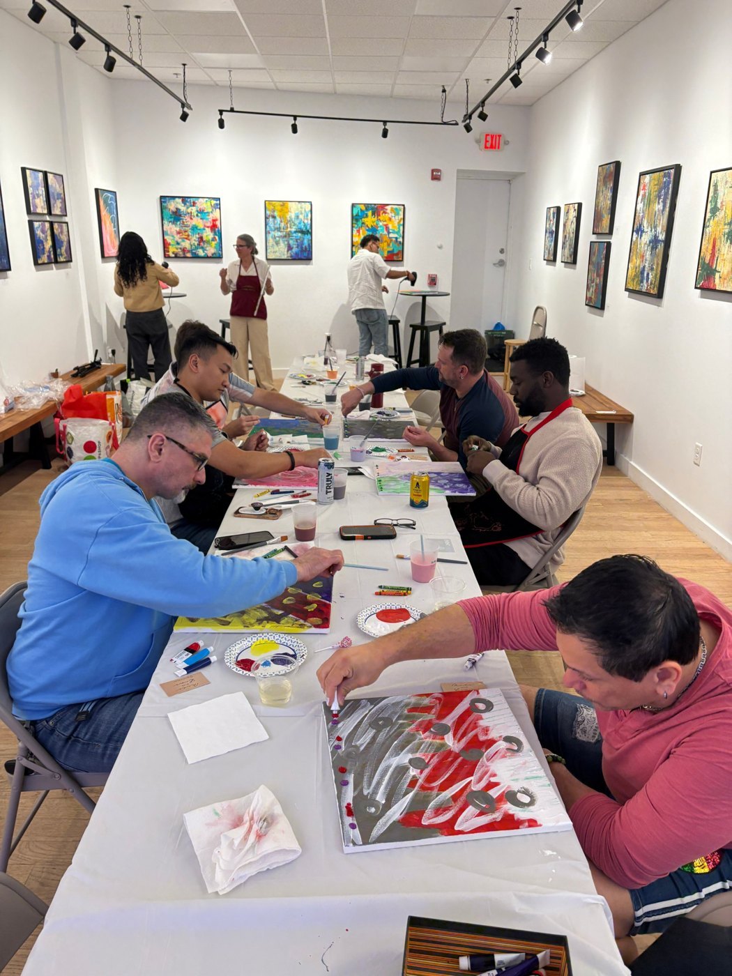 Guests painting at a long table in the gallery