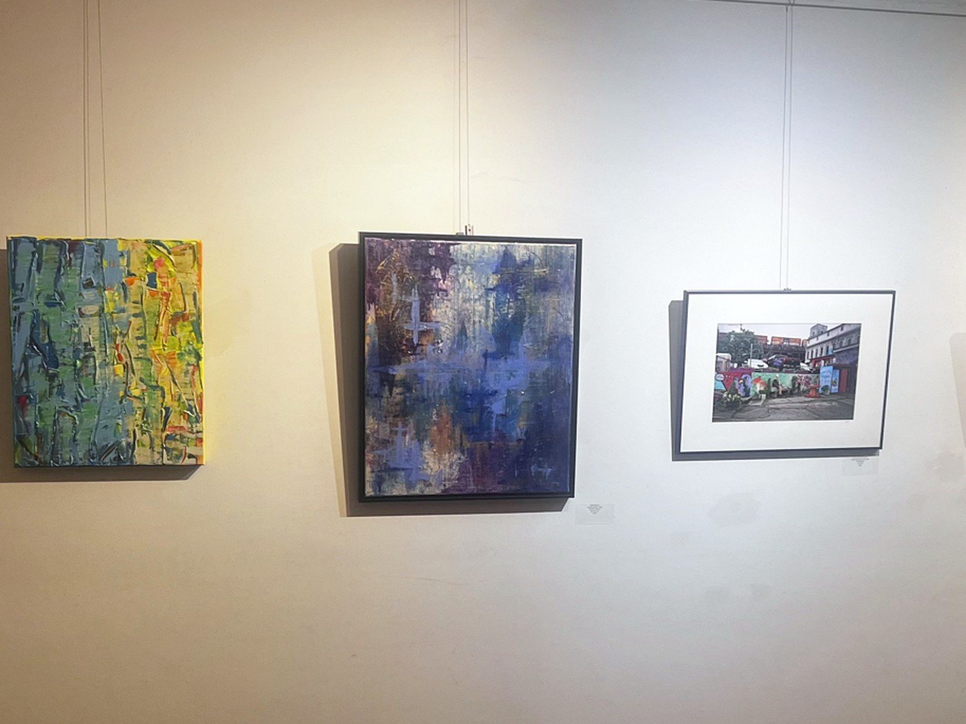 The gallery wall at The Fabric of We, with Edward's painting at center