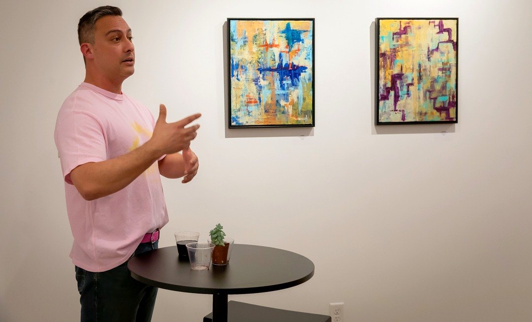 Edward Rocha talking about Ecos y reflejos in front of two paintings