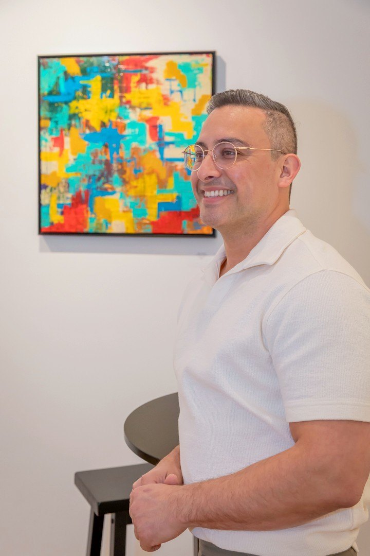Edward Rocha smiling beside one of his paintings