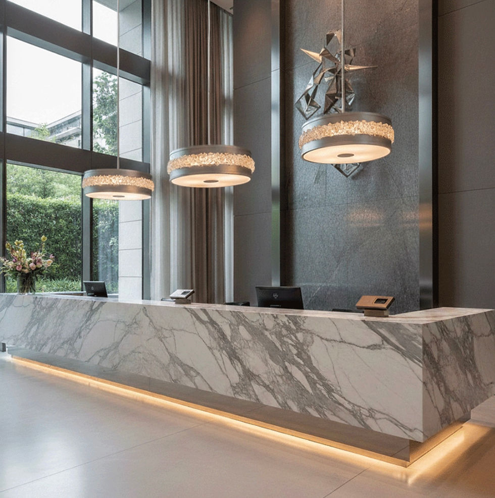 High angle view of a hotel foyer with 3  large drop light pendant installation creating vertical visual interest over reception desk in a modern interior – Rebecca Scott (UK, London & Yorkshire)