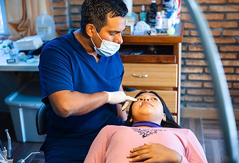 A dentist works with a young Huichol dental patient