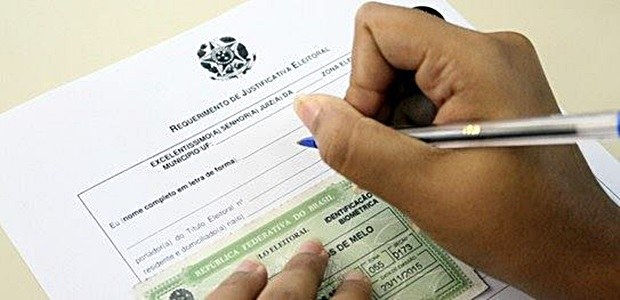 A imagem mostra um papel de requerimento de justificativa, um titulo e uma mão segurando uma caneta.
