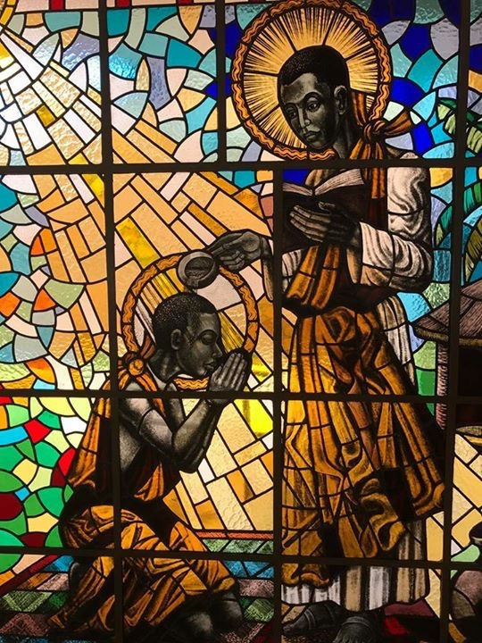 Beato Kizito sendo batizado pelo Beato Carlos Lwanga em Munyonyo, vitral do Santuário dos Mártires de Munyonyo.