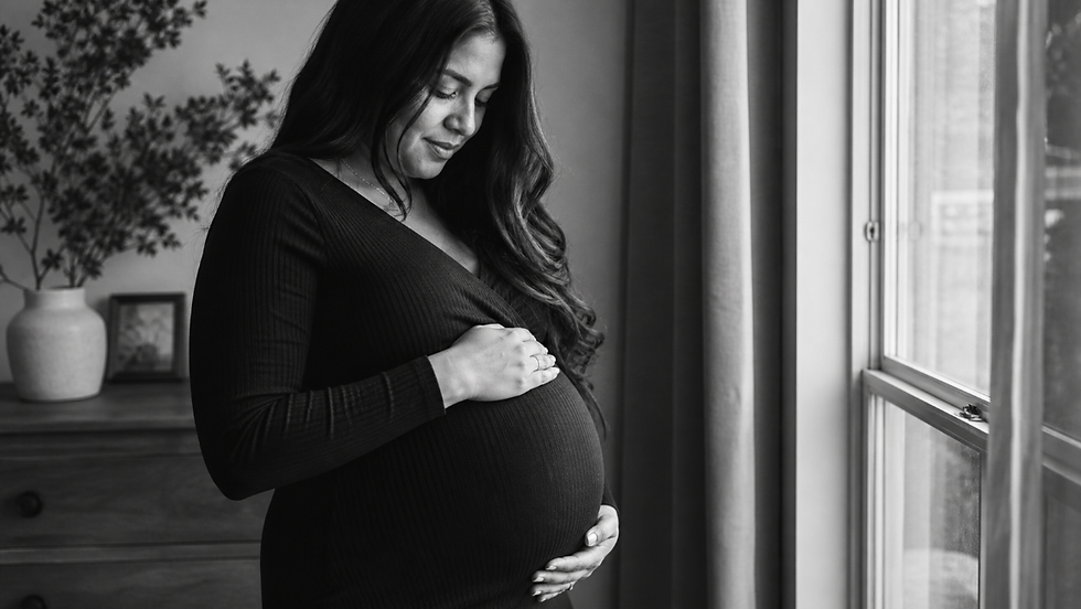 Pregnant woman gently cradling her baby bump during an indoor maternity shoot in Bexleyheath, South East London