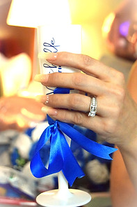 Close-up of bride's hand holding a personalised bridesmaid champagne flute with blue ribbon and engagement ring visible