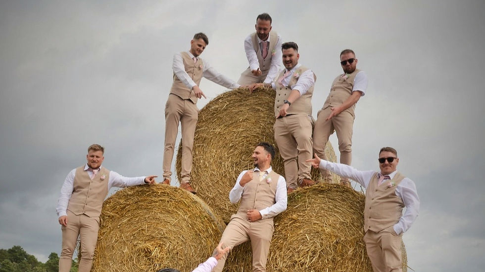 Groom and groomsmen laughing and posing on a stack of hay bales during a relaxed outdoor wedding in South East London
