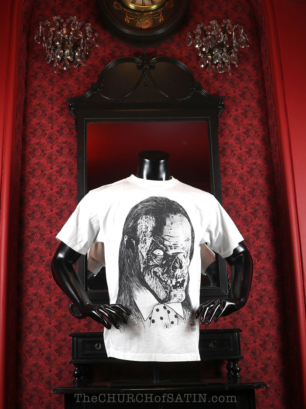 A vintage Tales from the Crypt horror movie t-shirt with the Cryptkeeper's oversize face on a white tee, photographed in front of a blood red Victorian decorated wall.