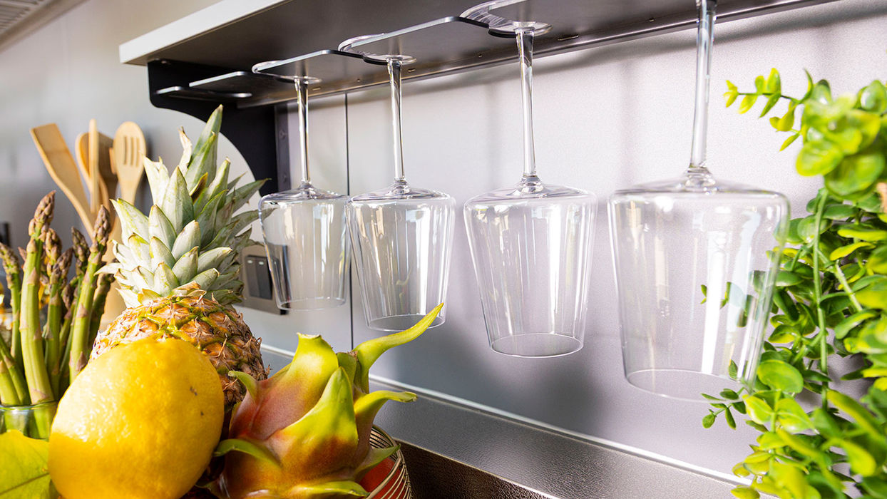 Edle Outdoor-Küche mit integrierten Weinglashaltern und frischen Früchten – stilvolle Ausstattung für komfortables Kochen und Genießen im geschützten Außenbereich.