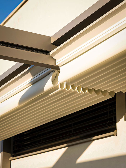 Detailaufnahme einer Screenroom Faltdach-Pergola mit gerafftem, hellem Stoffdach in einer präzisen Aluminium-Führungsschiene. Die Aufnahme zeigt die hochwertige Dachmechanik und den platzsparend zusammengefalteten Sonnenschutz.