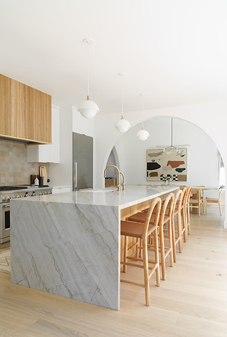 Modern kitchen with arched opening to dining room and waterfall counters 