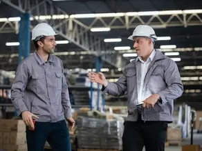 Supervisor having a serious conversation with an employee on a warehouse floor