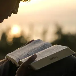 Pessoa fazendo devocional com Bíblia aberta ao amanhecer, representando como começar um devocional diário com Jesus