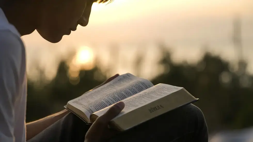 Pessoa fazendo devocional com Bíblia aberta ao amanhecer, representando como começar um devocional diário com Jesus