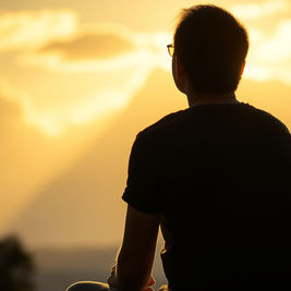Pessoa em silêncio ao entardecer sentindo o cuidado e a presença de Deus em momento de oração e reflexão.