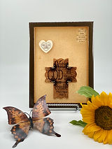 Plaque with a brown cross that contains the words "With God All Things Are Possible" (Matthew 19:26) set against a beige background.