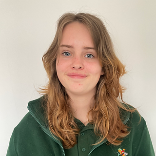 Photo of Lily, Bee's Knees Nursery and Pre-School's Level 3 apprentice. Lily is wearing the nursery's uniform and is smiling at the camera.