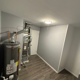 Newly updated utility closet housing a modern water heater and furnace system with clean drywall finishing.