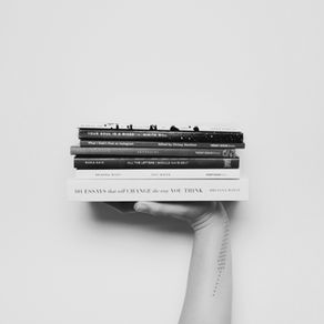 Hand holding a stack of books.