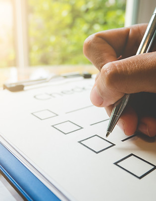 Close- up hand holding pen on check list paper and the format for filling in information i