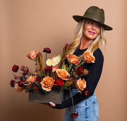 Kell Bonanno holding an artfully arranged bouquet of seasonal blooms, embodying the refined vision of White House Flowers