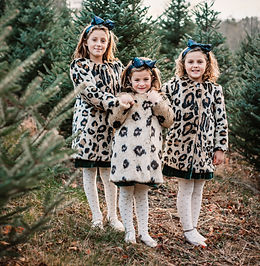 three sisters all dressed up for their tree farm photo shoot with jackie lenox