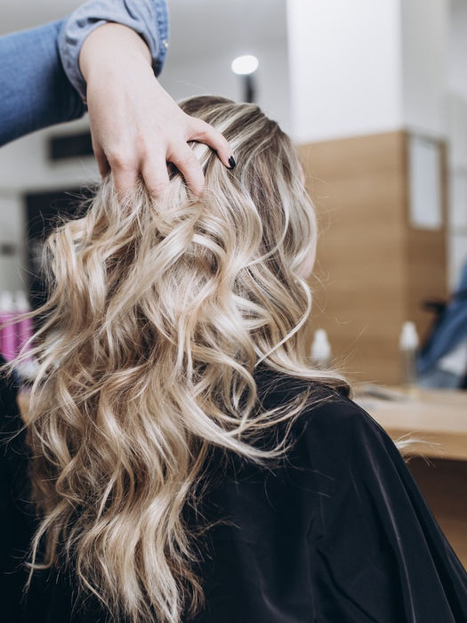 image of a women with blonde hair with lowlights and highlights getting her hair styled by our highly experienced hairstylist 