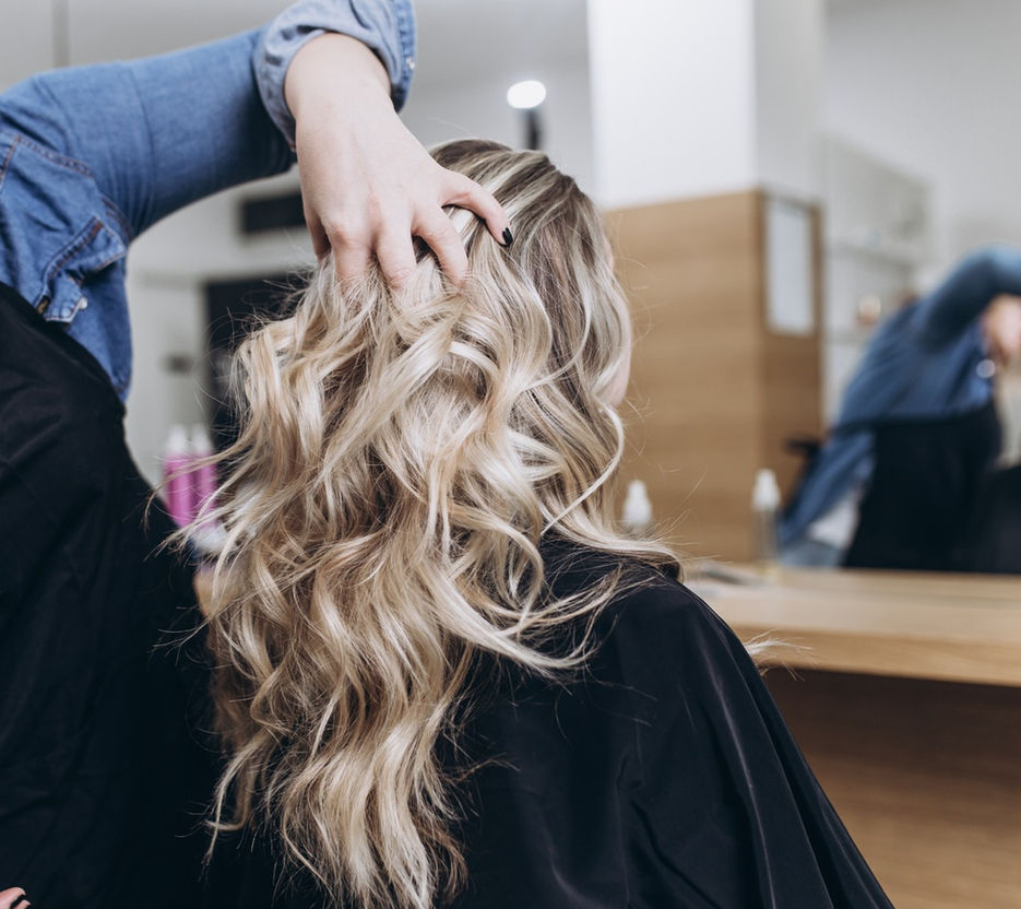 image of a women with blonde hair with lowlights and highlights getting her hair styled by our highly experienced hairstylist