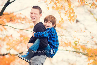 big brother giving a piggy back to little brother in autumn color leaves