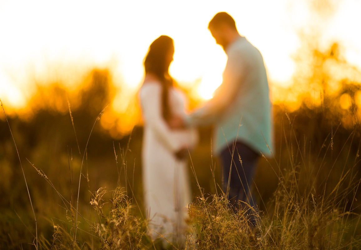 natural light magic hour outdoor photo of pregnant woman and man touching belly 4