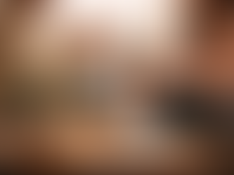 Deux femmes assises face à face dans un salon chaleureux échangent lors d’un entretien. Au premier plan, une table ronde en bois avec un bouquet de fleurs sauvages dans un vase, deux tasses, une bougie allumée et un carnet ouvert. L’arrière-plan est flou, créant une atmosphère douce et intime propice à la confiance et à la discussion.