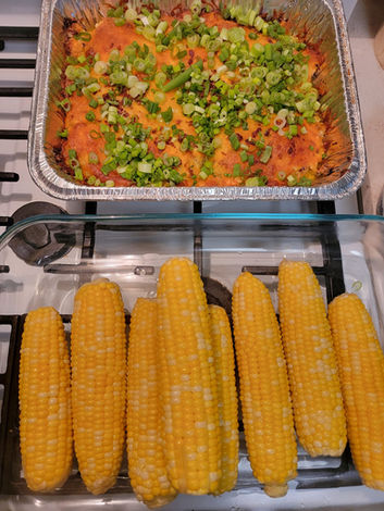 Picture of a dinner meal featuring an oven bake with a side of corn on the cob. 