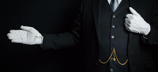 Portrait of Butler in Dark Suit and White Gloves Standing With Welcoming Gesture. Concept