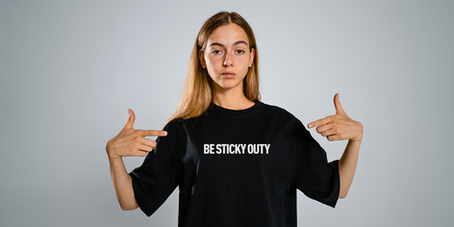 A woman wearing a shirt that says Be Sticky-Outy.