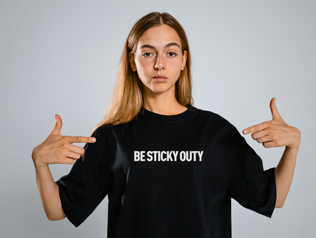 A woman wearing a shirt that says Be Sticky-Outy.