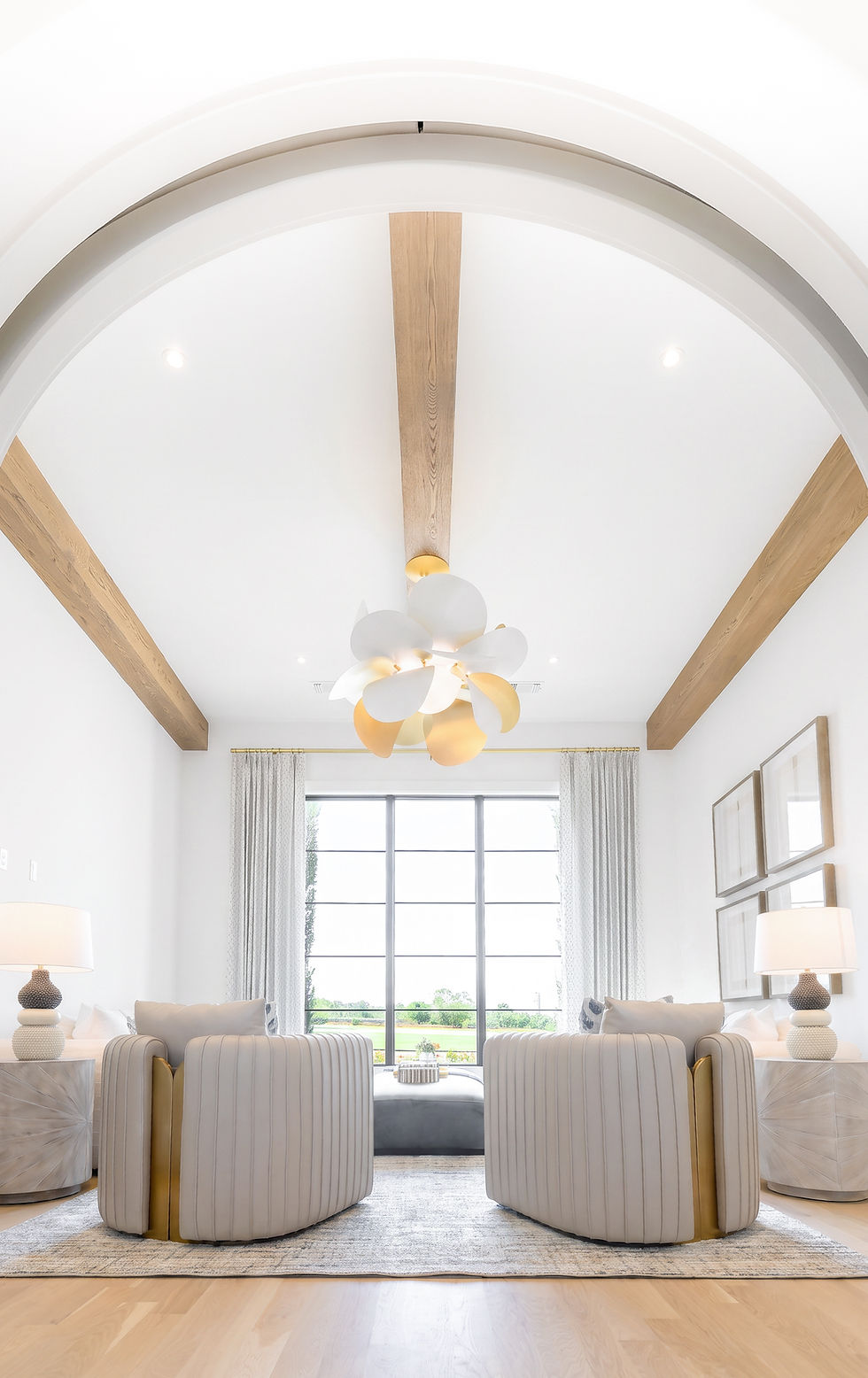 Elegant luxury living room featuring a dramatic vaulted arch, warm natural wood ceiling beams, sculptural statement lighting,