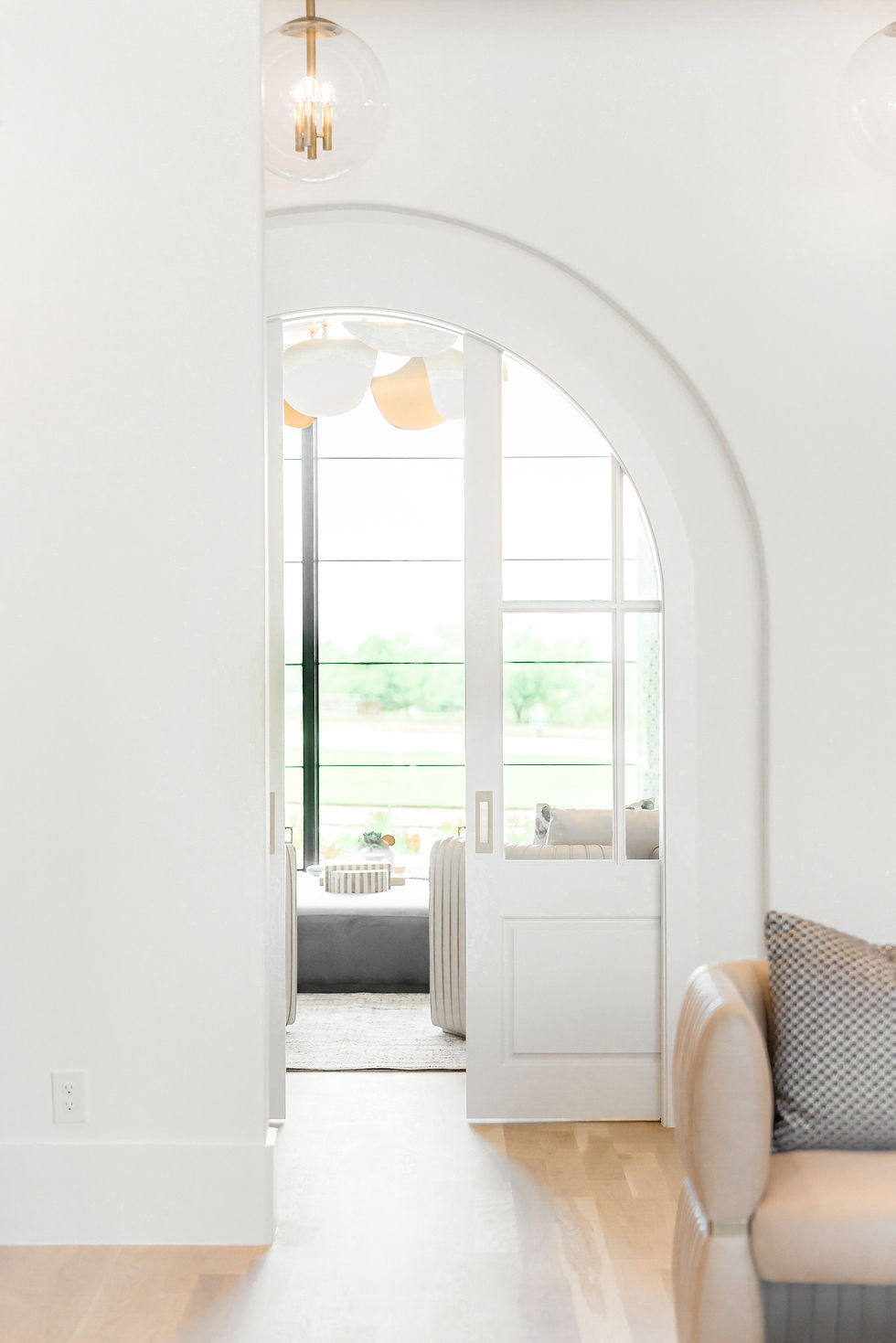 Elegant luxury interior featuring a grand arched opening with custom glass-paneled double doors, soft neutral finishes, light