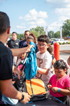 A few children are receiving free backpacks at a community charity event.