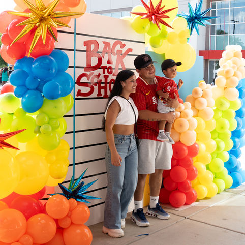 A couple and their toddler are posing at the photo booth at a community charity event.