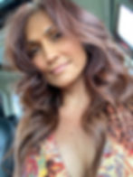 Woman with long, wavy brown hair taking a close-up selfie.