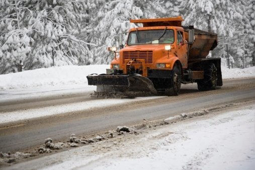 Snow removal truck clearing a snow-covered road during winter.
