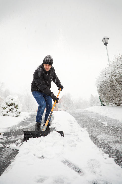 Worker shoveling snow from an outdoor area during winter.