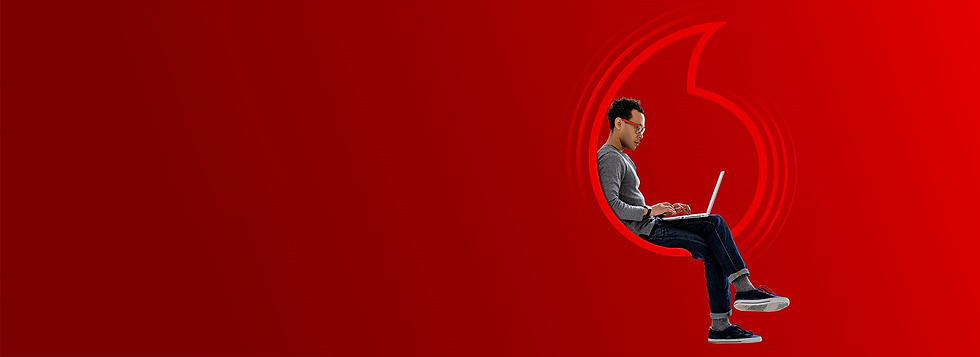 Man sitting in Vodafone logo wearing grey jumper and glasses with a laptop - Unlimited Data Plans