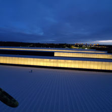 Night time shot showing 1 bank of windows half covered with black vinyl and the light coming through the remaining 2 and a half banks