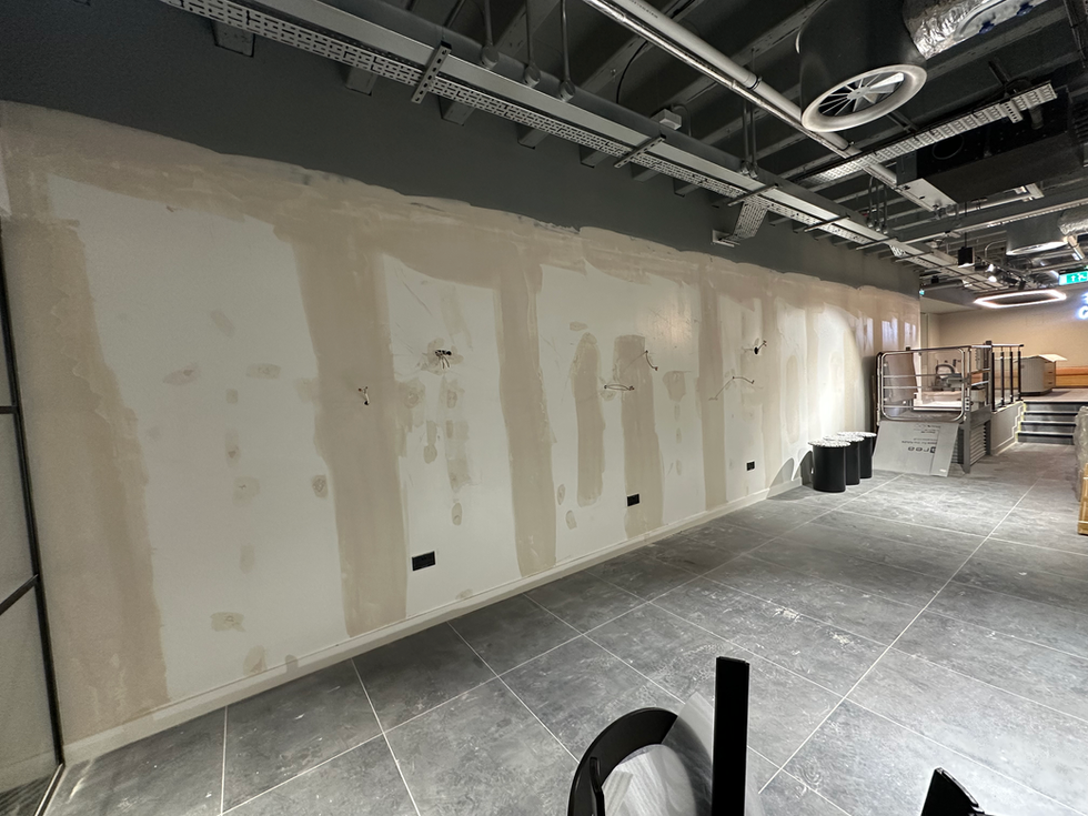 Plasterboard wall being repaired and primed prior to vinyl wrapping