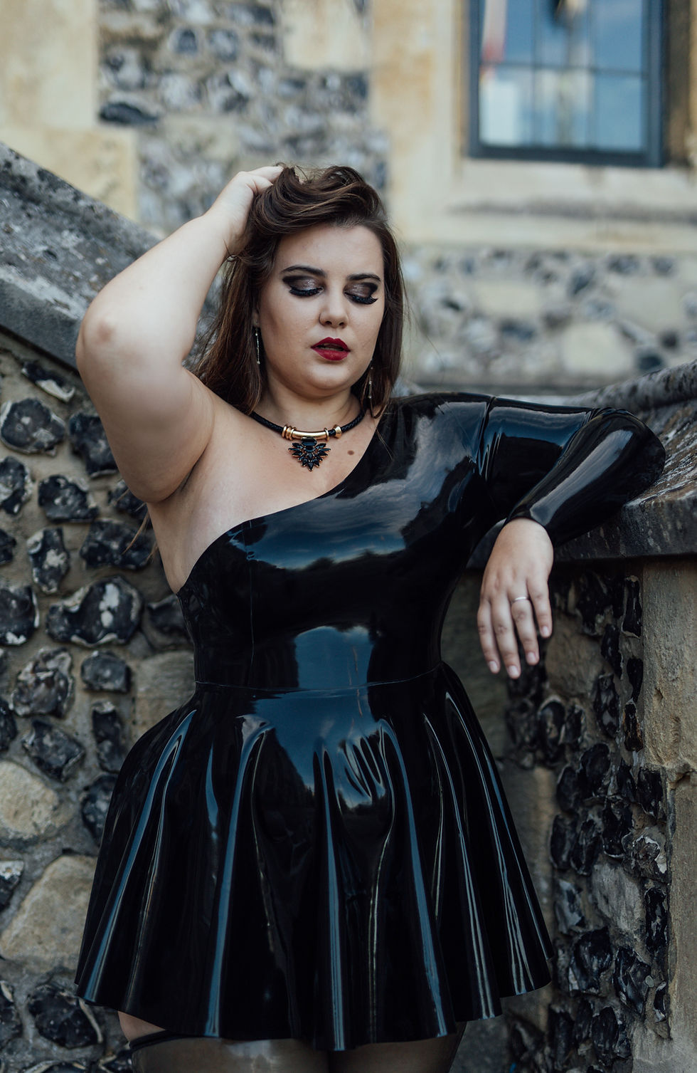 Thumbnail: latex dress being shown in black with one off shoulder design and one full length sleeve fitted torso and flared skirt